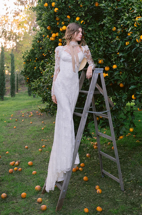 A bride standing on a ladder in a. wedding dress