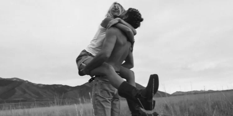 Man lifting a woman in a joyful embrace in a field, exemplifying the use of 'motion blur lightroom presets' in black and white photography.