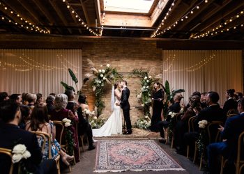 Bride and groom kiss under skylight and boho floral arch at their spring Arbory wedding in Chicago