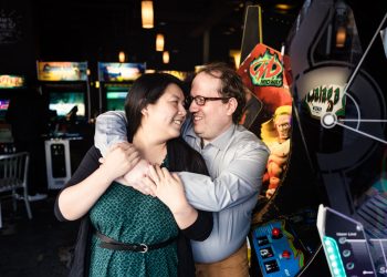 Romantic photo of couple getting cozy in arcade bar next to video game machine during Jersey City engagement session