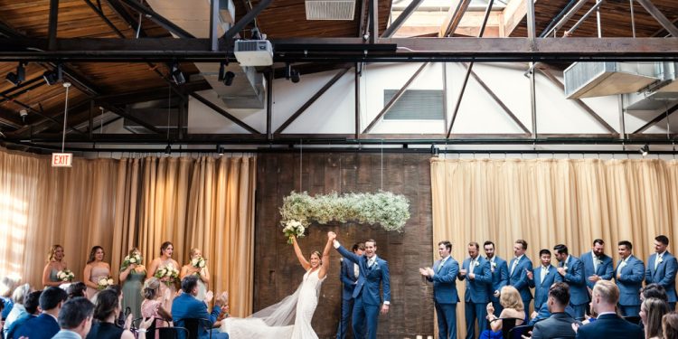 Just married bride and groom cheer with their guests under skylight at Ovation Chicago wedding ceremony