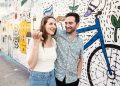 Candid photo of couple walking in front of mural on Milwaukee Avenue during their summer Wicker Park engagement session
