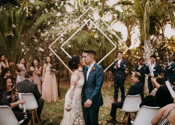Newlyweds kiss amid confetti at Acre Resort, one of the popular destination wedding venues in Mexico, surrounded by joyous guests and lush palm trees.