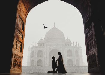 Silhouette of a couple in a marriage proposal moment at the Taj Mahal, framed by a grand arched entrance, highlighting engagement photography guide