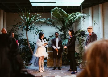 A wedding ceremony takes place in a lush, indoor venue with tropical plants, as the bride reads her vows to the groom. This captivating scene showcases the intimate and vibrant moments perfect for marketing your wedding photography business.