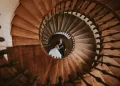 Overhead shot of newlyweds embracing at the bottom of a spiral staircase, showcasing the use of creative perspectives in wedding photography for social media appeal.